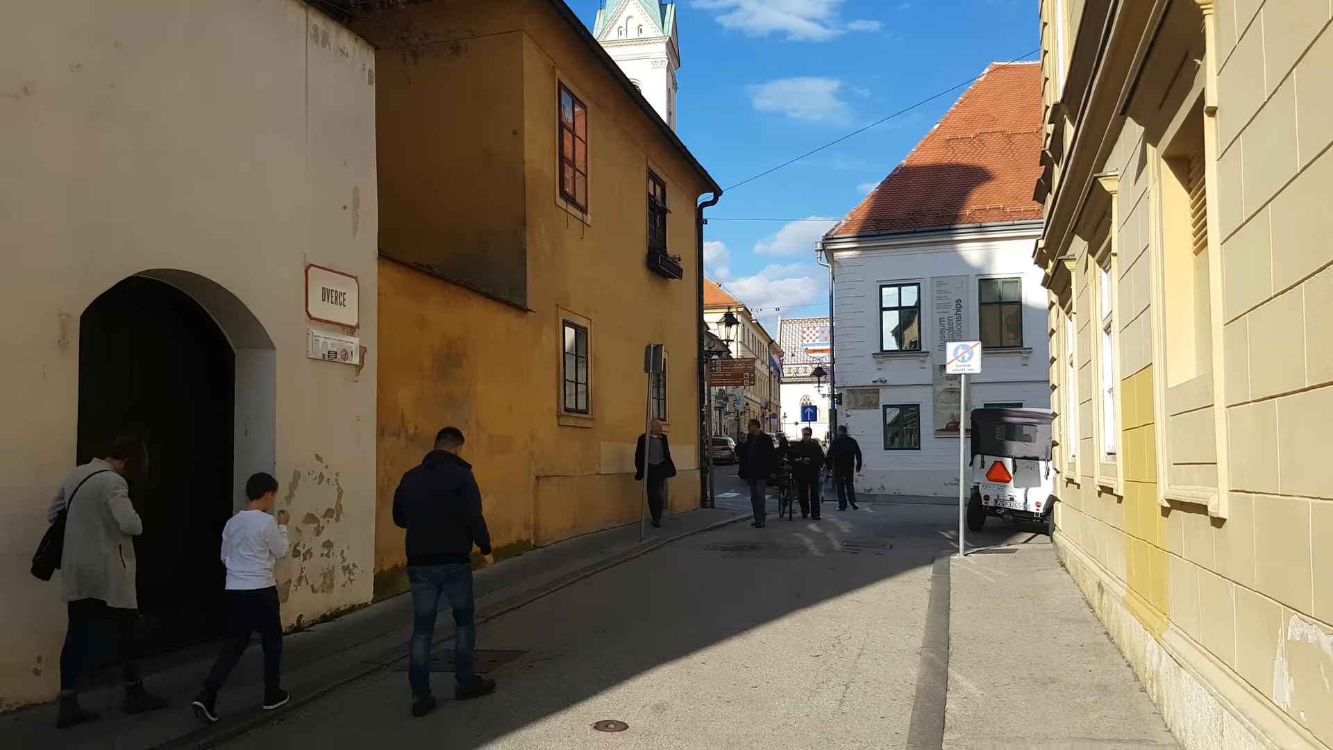 Kamena ulica u zagrebačkom Gornjem gradu sa starim zgradama i prolaznicima tokom sunčanog dana.
